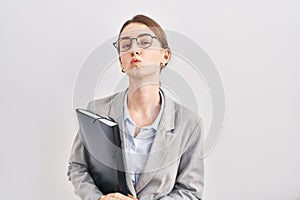 Young caucasian woman wearing business clothes and glasses looking at the camera blowing a kiss on air being lovely and sexy