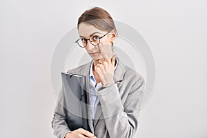 Young caucasian woman wearing business clothes and glasses pointing to the eye watching you gesture, suspicious expression