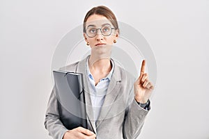 Young caucasian woman wearing business clothes and glasses pointing up looking sad and upset, indicating direction with fingers,