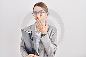 Young caucasian woman wearing business clothes and glasses shocked covering mouth with hands for mistake