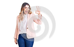 Young caucasian woman wearing business clothes smiling positive doing ok sign with hand and fingers