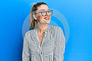 Young caucasian woman wearing business shirt and glasses looking to side, relax profile pose with natural face and confident smile