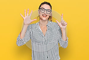 Young caucasian woman wearing business shirt and glasses showing and pointing up with fingers number seven while smiling confident
