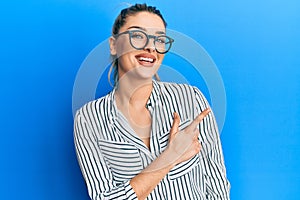 Young caucasian woman wearing business shirt and glasses smiling cheerful pointing with hand and finger up to the side