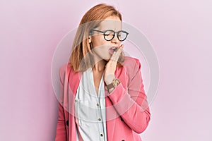 Young caucasian woman wearing business style and glasses bored yawning tired covering mouth with hand