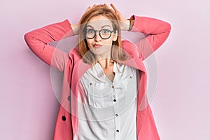 Young caucasian woman wearing business style and glasses doing bunny ears gesture with hands palms looking cynical and skeptical