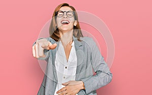 Young caucasian woman wearing business style and glasses laughing at you, pointing finger to the camera with hand over body, shame