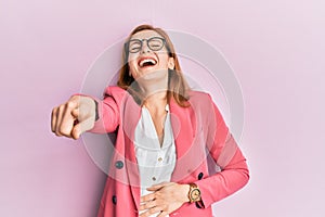 Young caucasian woman wearing business style and glasses laughing at you, pointing finger to the camera with hand over body, shame