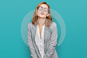 Young caucasian woman wearing business style and glasses looking at the camera blowing a kiss on air being lovely and sexy