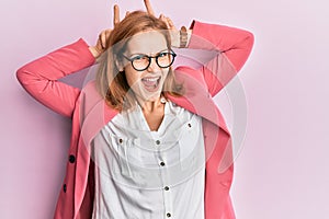 Young caucasian woman wearing business style and glasses posing funny and crazy with fingers on head as bunny ears, smiling