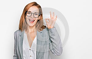 Young caucasian woman wearing business style and glasses smiling positive doing ok sign with hand and fingers