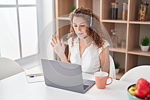 Young caucasian woman wearing call center agent headset working from home looking positive and happy standing and smiling with a