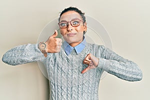 Young caucasian woman wearing casual clothes and glasses doing thumbs up and down, disagreement and agreement expression