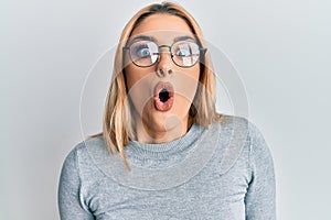 Young caucasian woman wearing casual clothes and glasses scared and amazed with open mouth for surprise, disbelief face