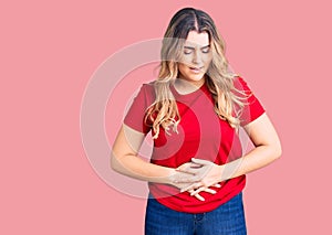 Young caucasian woman wearing casual clothes with hand on stomach because indigestion, painful illness feeling unwell