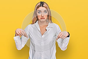 Young caucasian woman wearing casual clothes pointing down looking sad and upset, indicating direction with fingers, unhappy and