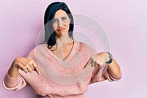 Young caucasian woman wearing casual clothes pointing down looking sad and upset, indicating direction with fingers, unhappy and