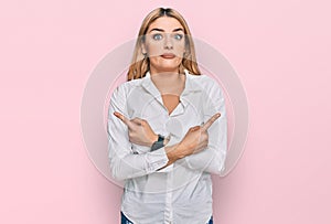 Young caucasian woman wearing casual clothes pointing to both sides with fingers, different direction disagree