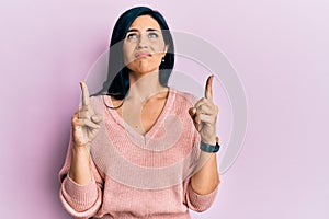 Young caucasian woman wearing casual clothes pointing up looking sad and upset, indicating direction with fingers, unhappy and