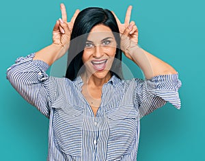 Young caucasian woman wearing casual clothes posing funny and crazy with fingers on head as bunny ears, smiling cheerful