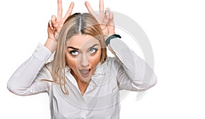 Young caucasian woman wearing casual clothes posing funny and crazy with fingers on head as bunny ears, smiling cheerful