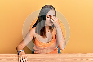 Young caucasian woman wearing casual clothes sitting on the table tired rubbing nose and eyes feeling fatigue and headache