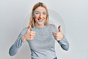 Young caucasian woman wearing casual clothes success sign doing positive gesture with hand, thumbs up smiling and happy