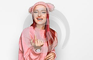 Young caucasian woman wearing casual clothes and wool cap beckoning come here gesture with hand inviting welcoming happy and