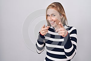 Young caucasian woman wearing casual navy sweater pointing fingers to camera with happy and funny face