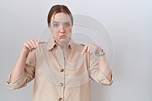 Young caucasian woman wearing casual shirt pointing down looking sad and upset, indicating direction with fingers, unhappy and