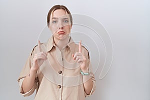 Young caucasian woman wearing casual shirt pointing up looking sad and upset, indicating direction with fingers, unhappy and