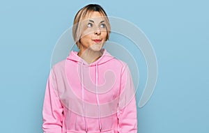 Young caucasian woman wearing casual sweatshirt smiling looking to the side and staring away thinking