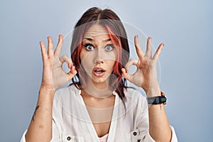Young caucasian woman wearing casual white shirt over isolated background looking surprised and shocked doing ok approval symbol