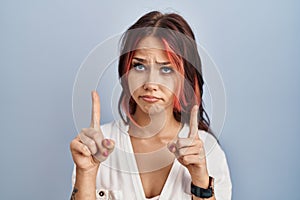 Young caucasian woman wearing casual white shirt over isolated background pointing up looking sad and upset, indicating direction