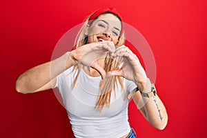 Young caucasian woman wearing casual white t shirt smiling in love doing heart symbol shape with hands