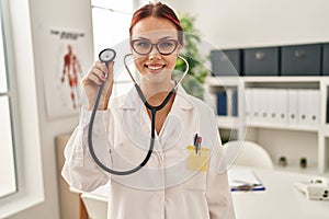 Young caucasian woman wearing doctor uniform using stethoscope looking positive and happy standing and smiling with a confident