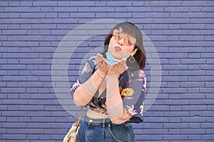 Young caucasian woman wearing face mask wrongly and throwing kisses to the camera