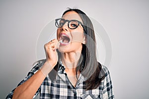 Young caucasian woman wearing glasses brushing her teeth using tooth brush and oral paste, cleaning teeth and tongue as healthy