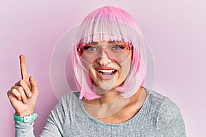 Young caucasian woman wearing pink wig and heart sunglasses smiling happy pointing with hand and finger to the side