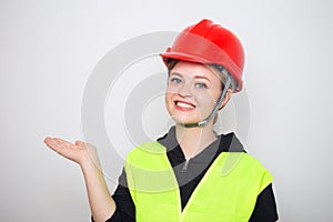 Young caucasian woman wearing red safety hard hat and reflective vest, smiling