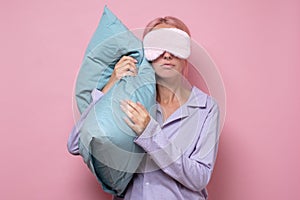 Young caucasian woman wearing sleep mask during sleeping holding a pillow