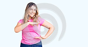 Young caucasian woman wearing sportswear gesturing with hands showing big and large size sign, measure symbol
