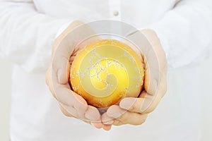 Young caucasian woman in white clothes holds in hands beautiful big golden fir tree decorative glittering ball. Christmas New Year