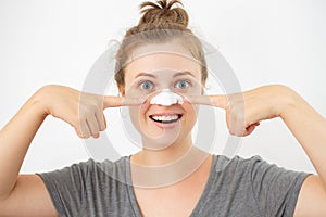 Young caucasian woman with white peel mask on her nose, removing blackheads