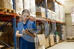 Young caucasian woman worker use tablet technology checking stock in warehouse cargo goods storage. Products Inventory management