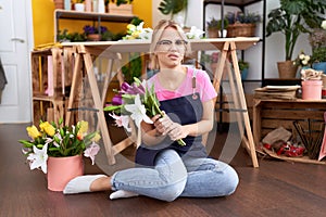Young caucasian woman working at florist shop sitting of floor clueless and confused expression