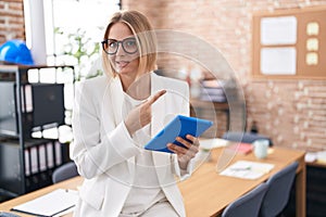 Young caucasian woman working at the office wearing glasses pointing aside worried and nervous with forefinger, concerned and