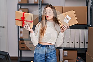 Young caucasian woman working at small business ecommerce looking at the camera blowing a kiss being lovely and sexy