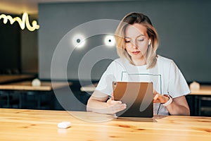 Young caucasian woman working on a touchscreen tablet in a cafe. Copyspace