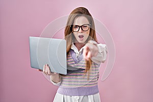 Young caucasian woman working using computer laptop pointing displeased and frustrated to the camera, angry and furious with you